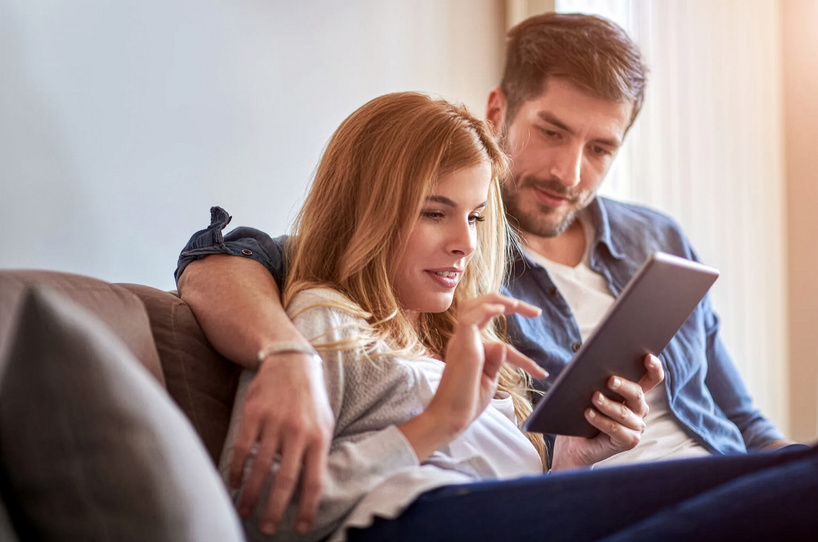 Mann und Frau schauen gemeinsam auf ein Tablet, auf dem die Website der Bank BSU geöffnet ist.